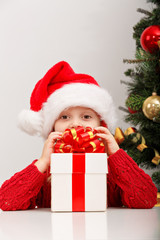 Fototapeta na wymiar Happy little girl with gift box near the Christmas tree