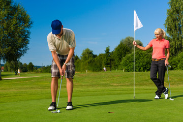 Obraz premium Young sportive couple playing golf on a course