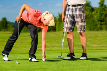 Obraz premium Young sportive couple playing golf on a course