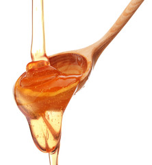 Honey dripping from a wooden honey dipper isolated on white back