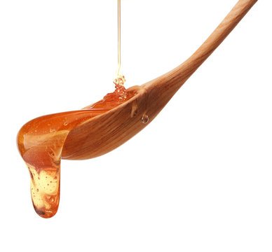 Honey dripping from a wooden honey dipper isolated on white back