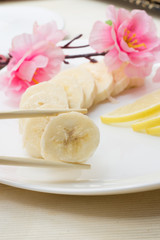 Sliced banana on white plate decorated with sakura and lemon
