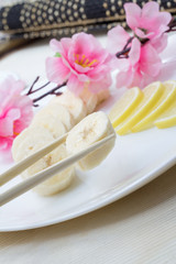 Obraz na płótnie Canvas Sliced banana on white plate decorated with sakura and lemon