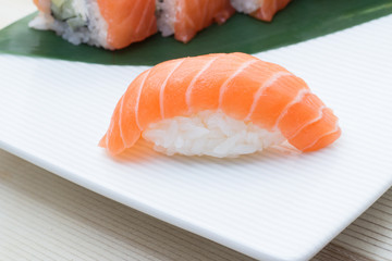 Salmon sushi nigiri on white plate with philadelphia roll