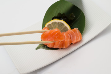 Salmon sushi sashimi with lemon and  and chopsticks