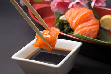 Salmon sushi sashimi with lemon and soy sauce and chopsticks