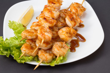 Shrimp shashlik on white plate with sauce and salad