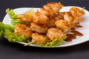 Shrimp shashlik on white plate with sauce and salad