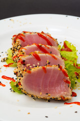 Tuna fillet on white dish with sesame salad and soy sause