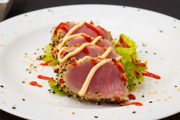 Tuna fillet on white dish with sesame salad and soy sause