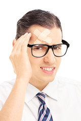Serious young man with plaster on his forehead having a headache