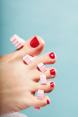 foot pedicure applying red toenails on blue