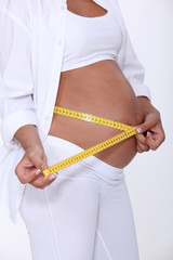 Pregnant women using tape measure to measure stomach