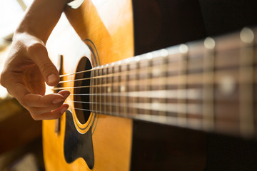 Close-up female hand playing on acoustic guitar..