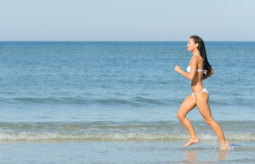Sensual brunette running on the beach. Place for text.