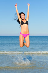 Happy woman jumping in the water at the beach