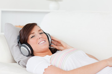 Pretty brunette female relaxing with her headphones while lying