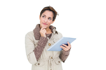 Pensive cute brunette in winter fashion holding tablet