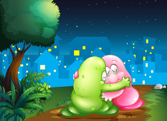 A pink and a green couple monsters hugging each other at the pat