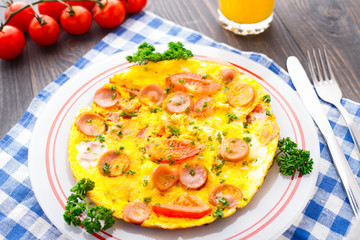 Omelette with slices of sausage and tomato