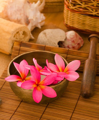 Pink frangipani with pebbles on woven bamboo mat