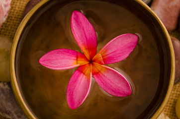 Obraz na płótnie Canvas Pink frangipani with pebbles on woven bamboo mat