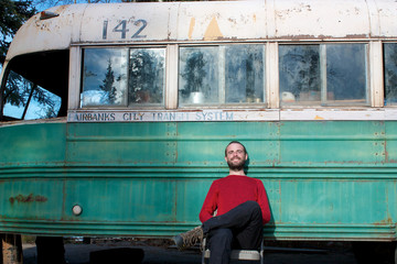 Young man sitting in front of Magic Bus from Into The Wild