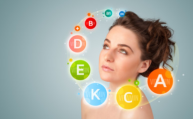 Pretty young girl with colorful vitamin icons and symbols