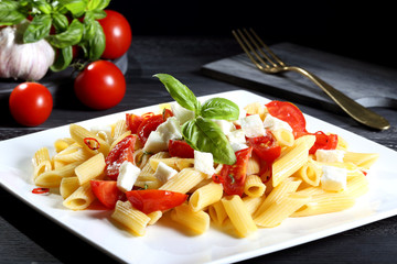pasta italiana penne pomodoro e mozzarella sfondo grigio