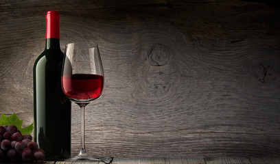 Weinglas mit Flasche vor Holzwand