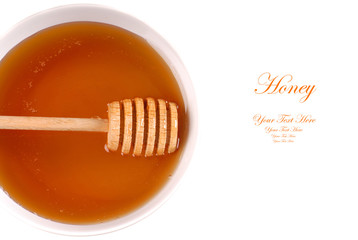 Closeup of a bowl of amber honey with a honey wand isolated on w