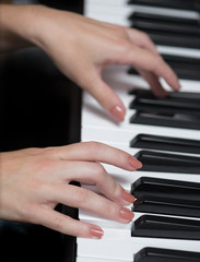 Fototapeta premium A hand of a girl playing piano. Selective focus.