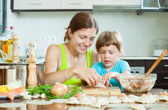  woman with child cooking fish pelmeni (pelmeni), today together