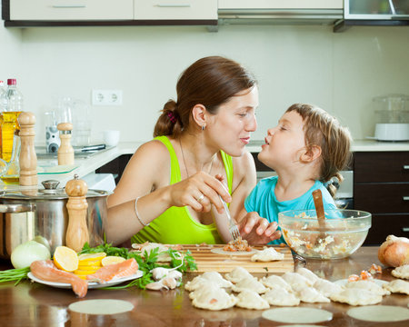 woman with girl cooking fish dumplings together  at home kitchen
