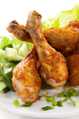 Grilled chicken legs and vegetables on white background