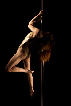 Sexy young female pole dancer on black background