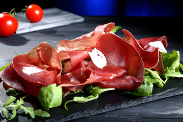 insalata bresaola su pietra nera sfondo blue