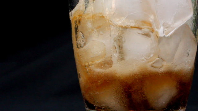 Pouring a glass of cola with ice cubes