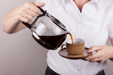Frau schüttet Kaffee in eine Tasse
