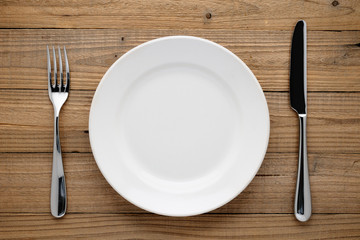 Plate, fork and knife on wooden background