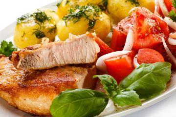 Grilled steaks, boiled potatoes and vegetable salad