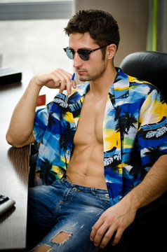 Handsome young man with open shirt at his office desk