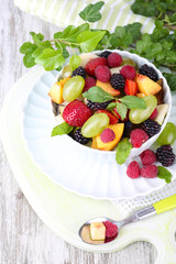 Fruit salad in bowl, on wooden table background