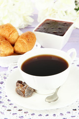 Tasty croissants and cup of coffee on table close-up