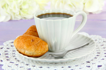 Tasty croissants and cup of coffee on table close-up