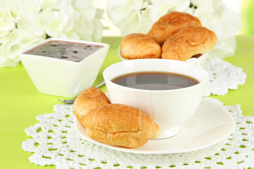 Tasty croissants and cup of coffee on table close-up