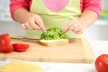 Happy smiling woman in kitchen preparing  sandwich, close up