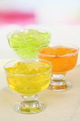Tasty jelly cubes in bowls on table on light background