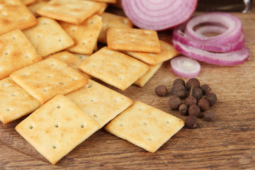 Delicious crackers with onion and spices on wooden background