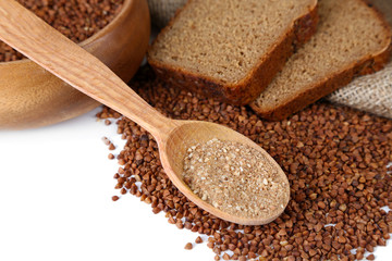 Buckwheat groats in bowl and wooden spoon closeup